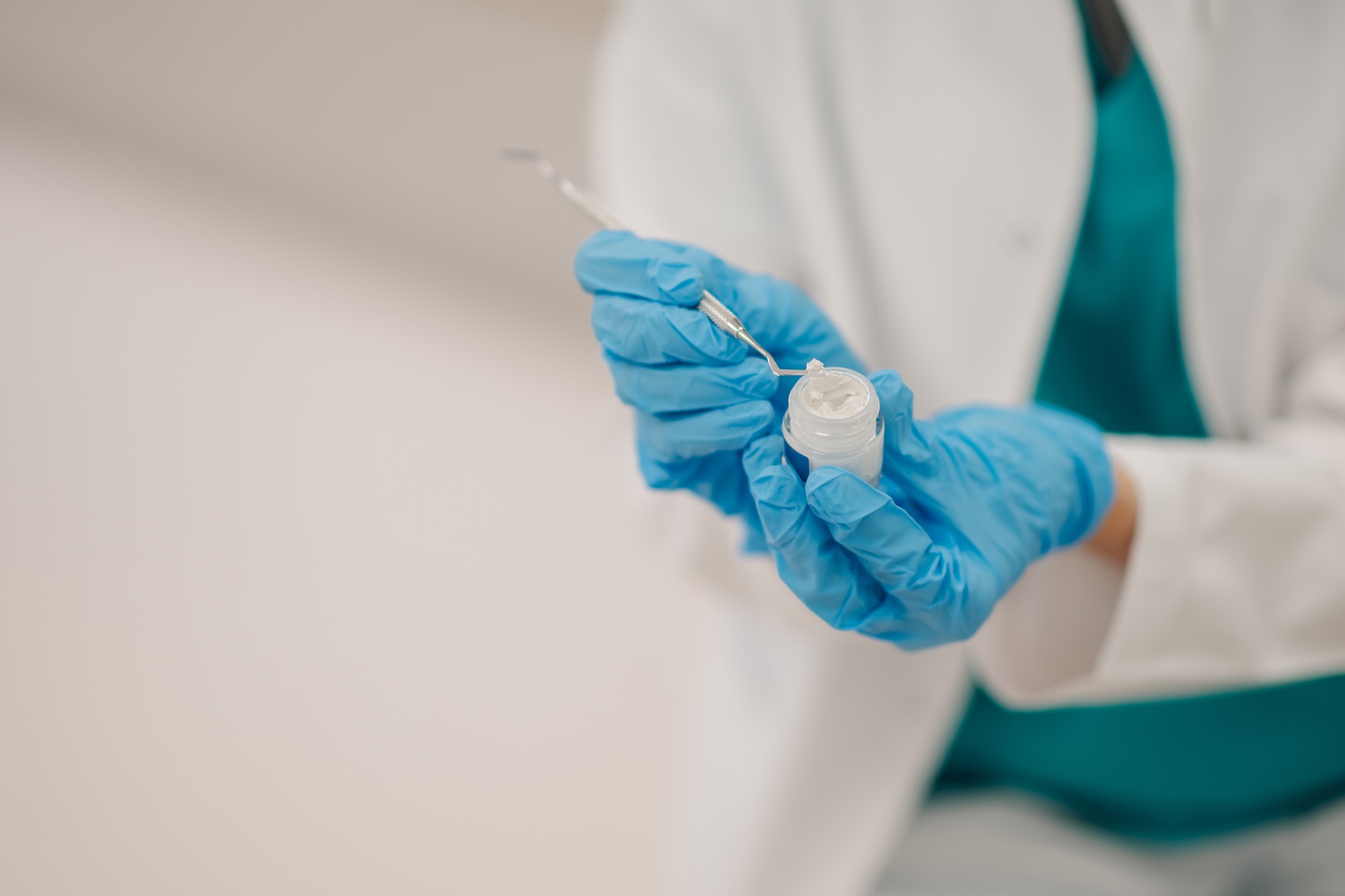 Dentist picking filling material with dental probe in clinic